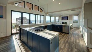 A modern kitchen with a large island, ample natural light, and a view of the ocean. - 6BR - 6.5 Bath - Sleeps 14-Amazing Sunsets, Creating Lifelong Memories Together  (Salvo)