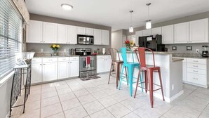 A modern kitchen with white cabinets, stainless steel appliances, and a central island with bar stools.
