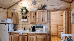 Cocina de cabaña de madera con una isla central, armarios de madera, microondas, cafetera y fregadero.