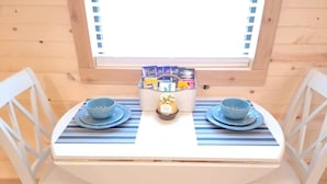 Una mesa de comedor con dos platos y cuencos azules, una cesta de aperitivos y una ventana arriba.