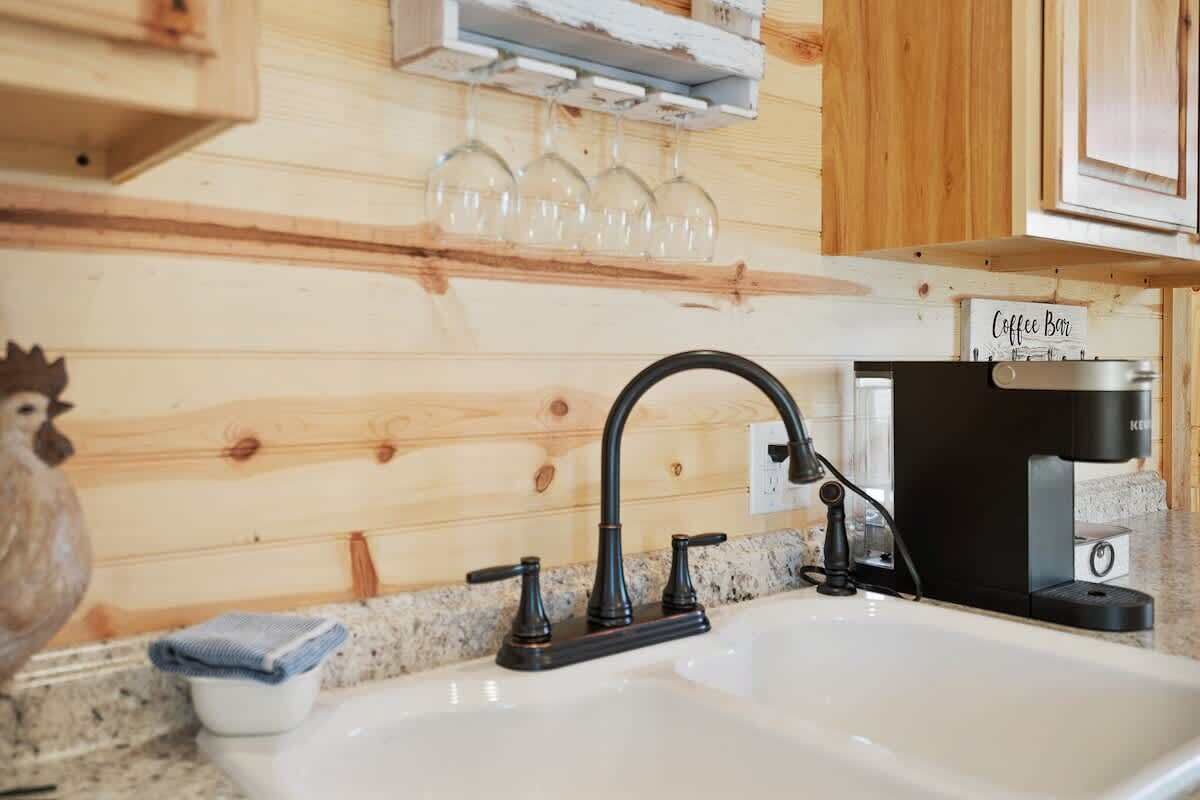 A kitchen with a white sink, black faucet, and a coffee maker on the countertop.