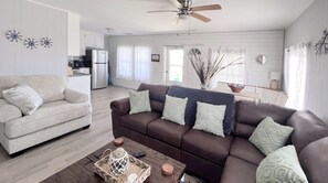 A modern living room with a grey sofa, a brown sofa with patterned cushions, a wooden coffee table, and a ceiling fan. - Barefoot Beach: Spectacular Family Beach Retreat! (Atlantic Beach)