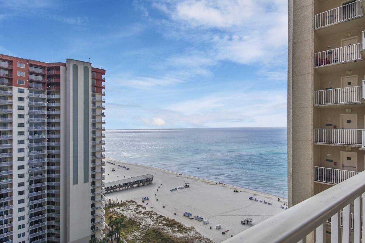 A high-rise building with multiple balconies overlooking a beach.