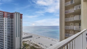A high-rise building with multiple balconies overlooking a beach.