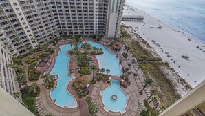 A high-rise hotel with multiple swimming pools, a beach, and a view of the ocean.