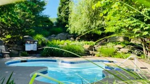 Ein Schwimmbecken, umgeben von üppiger Vegetation und Felsen.