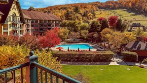 Ein Hotel mit Pool, umgeben von Herbstlaub und einer hügeligen Landschaft.