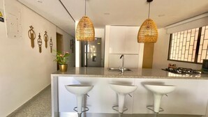 A kitchen with a central island, white bar stools, and hanging wicker pendant lights. - Casa de la Belleza, Uniquely designed 7 bedroom home (Cartagena de Indias)