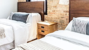 Camera da letto con due letti, un muro in mattoni e un'ampia finestra.