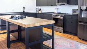 Una cucina moderna con mobili scuri, un frigorifero in acciaio inossidabile e un tavolo da pranzo in legno.