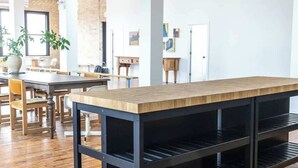 Un'ampia stanza con un lungo tavolo in legno, scaffali neri e condotti a vista sul soffitto.