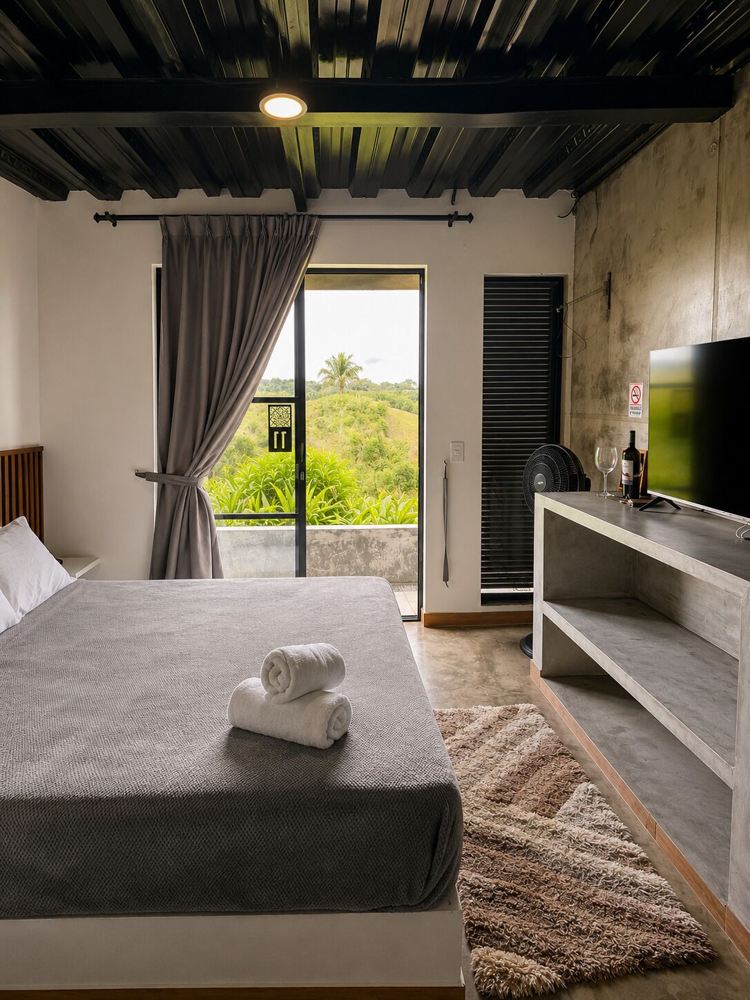 A modern bedroom with a bed, a desk, and a television.