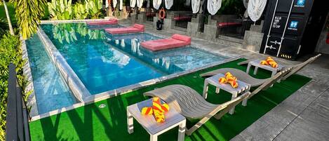 A swimming pool with lounge chairs and a covered area with curtains.