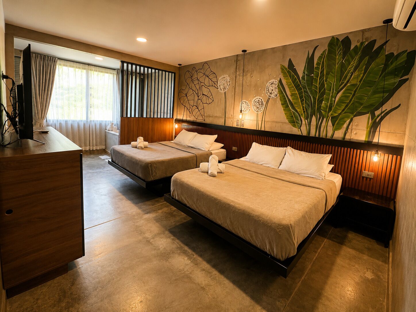 Habitación de hotel con dos camas, un escritorio y una planta grande.