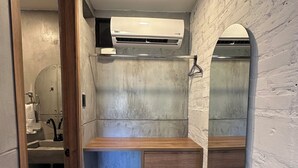 Een badkamer met een houten wastafelmeubel, een spiegel en een wand met een witte textuur.