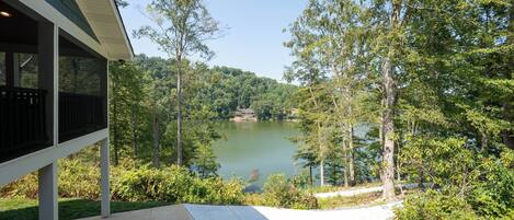 A covered patio with a view of a lake surrounded by trees.