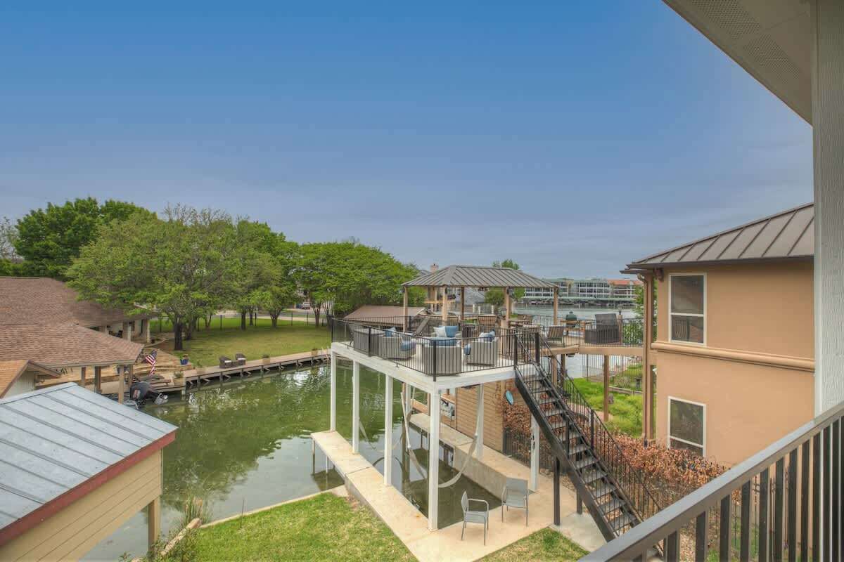 Una zona residencial con un muelle que se adentra en el agua, rodeada de casas y árboles.