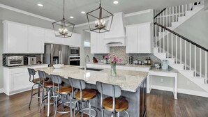 A spacious kitchen with a large island, bar stools, and pendant lighting.