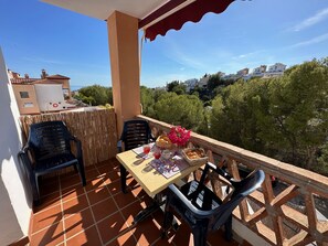 A terrace with a table set for two, featuring a basket of bread, a vase of flowers, and a bottle of red wine. - Nerja Paradise Rentals - Villa Aljamar 8a (Nerja)