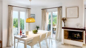 Un comedor con mesa, sillas, lámpara colgante y chimenea.