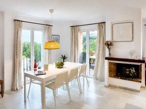 Un comedor con mesa, sillas, lámpara colgante y chimenea.