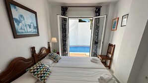 Habitación de hotel con dos camas, vista al mar, un cuadro enmarcado y una silla.