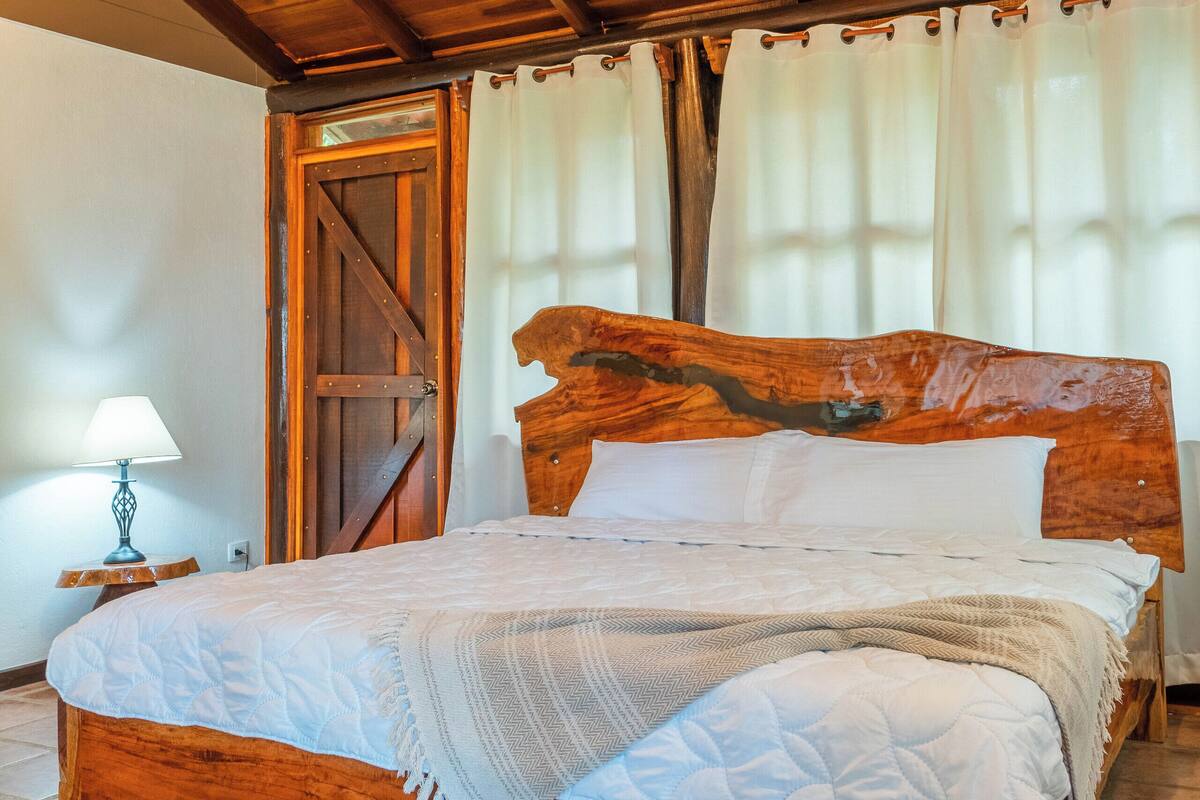A wooden bed with a headboard, a bedside lamp, and a door with curtains.