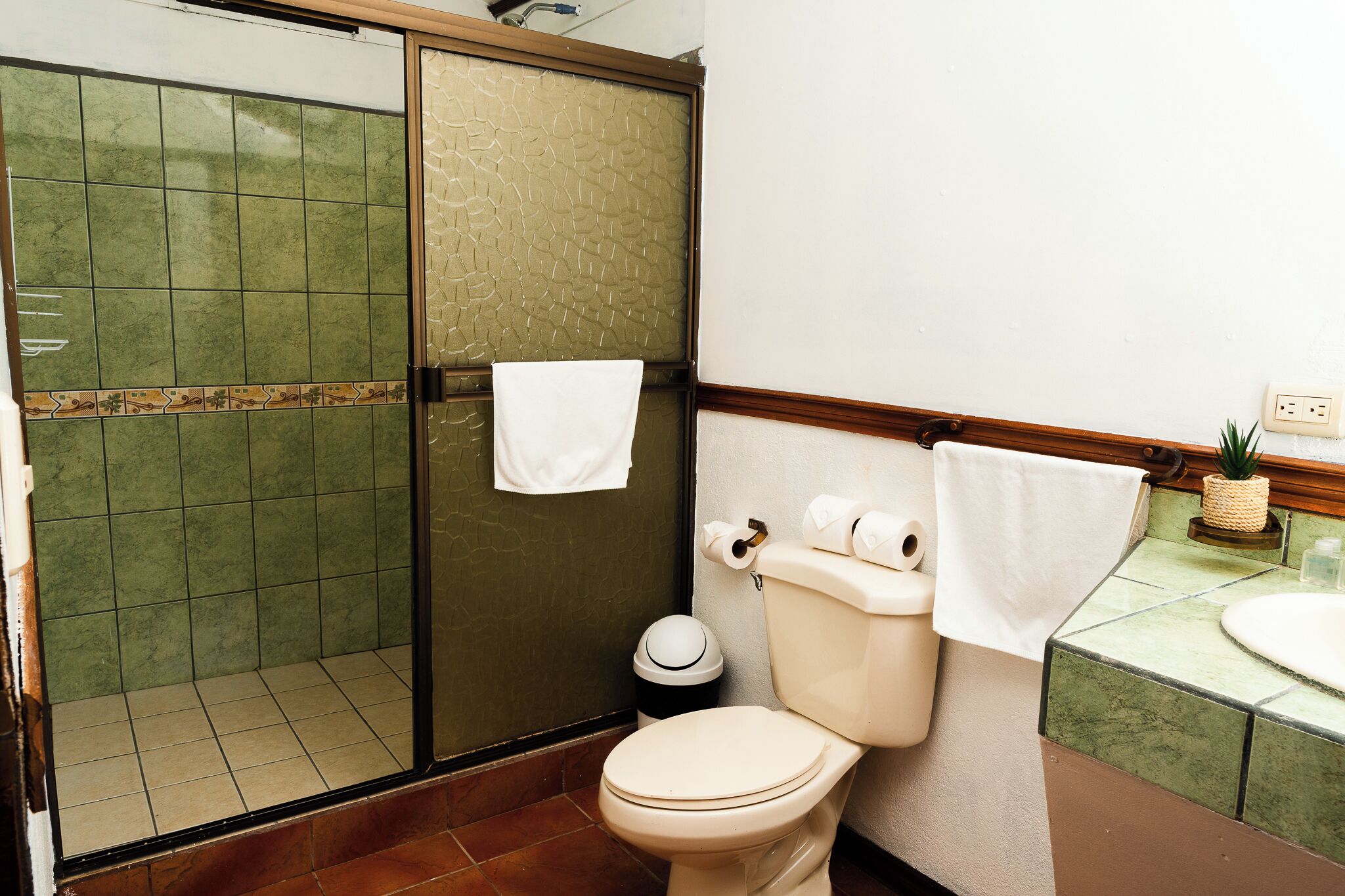 Un baño con inodoro, cabina de ducha y lavamanos.