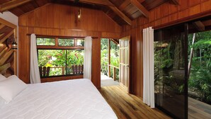Una stanza in legno con un letto, ampie finestre e vista sul verde.