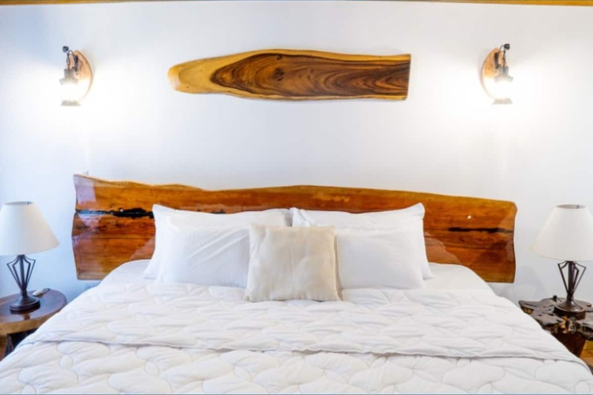 A bed with a wooden headboard, white bedding, and two bedside lamps.