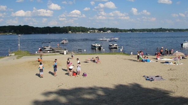A beach with people, boats, and a dock. - Sunnyside Lake Home at Conneaut Lake (Conneaut Lake)