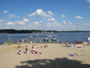 Une plage avec des gens, des bateaux et un quai.