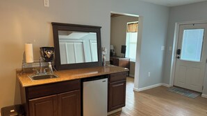 A modern kitchen with a built-in dishwasher, a large mirror, and a countertop with a paper towel holder. - Sunnyside Lake Home at Conneaut Lake (Conneaut Lake)