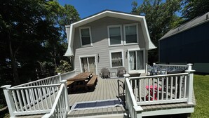 A two-story house with a deck, a covered patio, and a front door. - Sunnyside Lake Home at Conneaut Lake (Conneaut Lake)