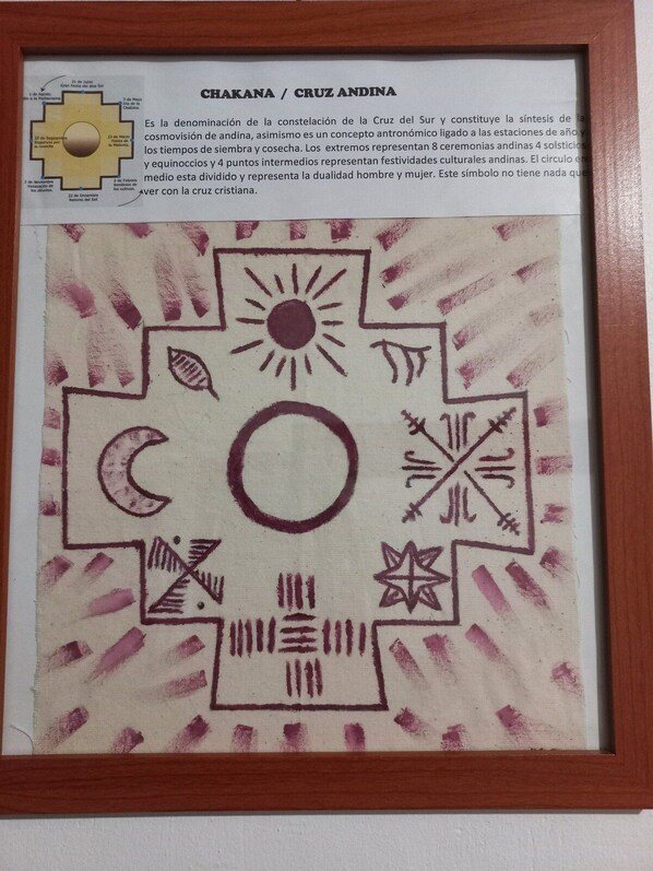 Un tapiz enmarco con símbolos que representan la constelación Chakana / Cruz Andina, incluyendo un sol, una luna y formas geométricas.