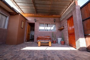 Un porche cubierto con un banco de madera, plantas en macetas y una puerta de madera.