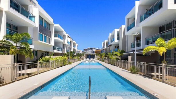 Un hôtel moderne doté d’une piscine centrale, entouré de bâtiments blancs agrémentés de balcons.