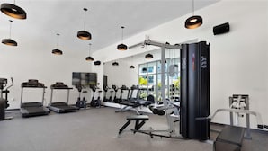 Une salle de sport moderne équipée de tapis de course, de vélos elliptiques et de matériel de musculation.