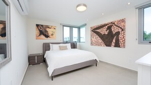 Une chambre à coucher moderne avec un lit, des tables de chevet et des œuvres d’art accrochées aux murs.
