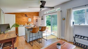A modern kitchen with wooden accents, a dining area with a wooden table and chairs, and a large sliding glass door leading to a garden. - 2 Mi to Duke University: Durham Tiny Home! (Durham)