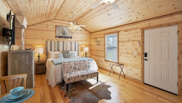 Une chambre confortable avec un plafond en bois, un lit recouvert d’une literie à motifs, des lampes de chevet et une porte.