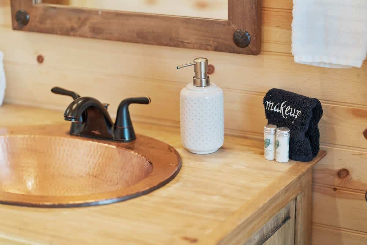 A wooden bathroom vanity with a round sink, a soap dispenser, and a towel rack labeled "makeup".