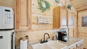 Une cuisine avec des meubles en bois, un évier blanc, un four à micro-ondes et une machine à café.