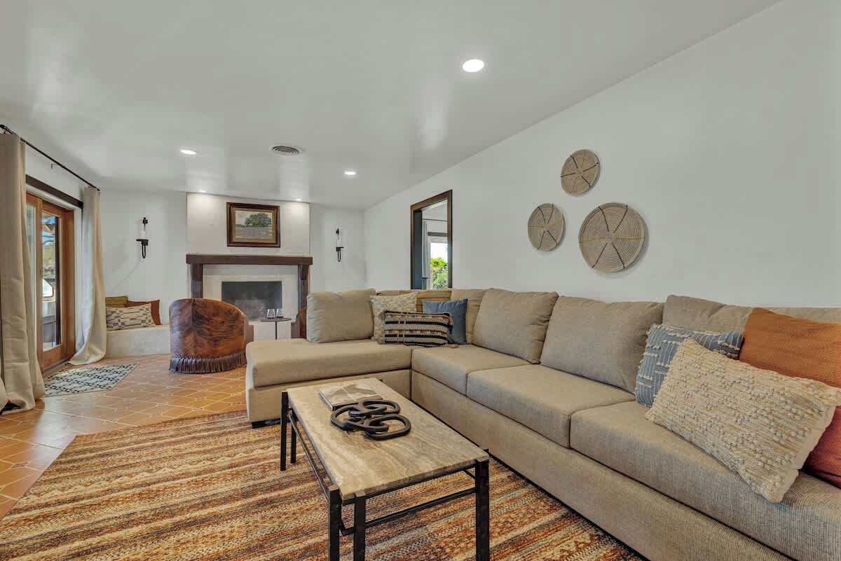 A modern living room with a sectional sofa, a wooden coffee table, and a patterned rug.