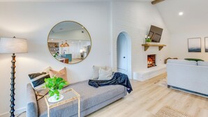 Una sala de estar moderna con un sofá gris, un espejo redondo, una lámpara de pie y una chimenea.