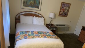 Una camera d'albergo con un letto, un comodino, una lampada, un condizionatore d'aria e un armadio.