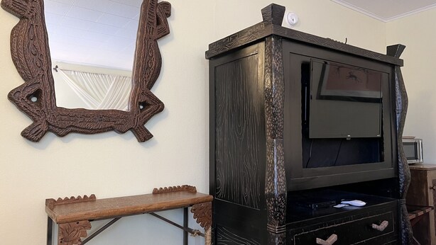 Una stanza con un mobile TV in legno, uno specchio e un tavolino.