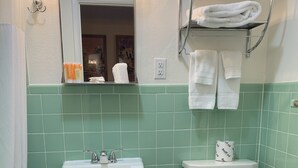 Un bagno con lavandino, water e specchio. Asciugamani appesi a un porta-asciugamani sopra il water.
