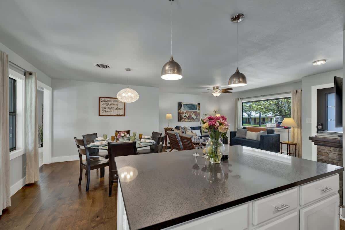 A spacious kitchen with a central island, pendant lighting, and a dining area with chairs and a table.