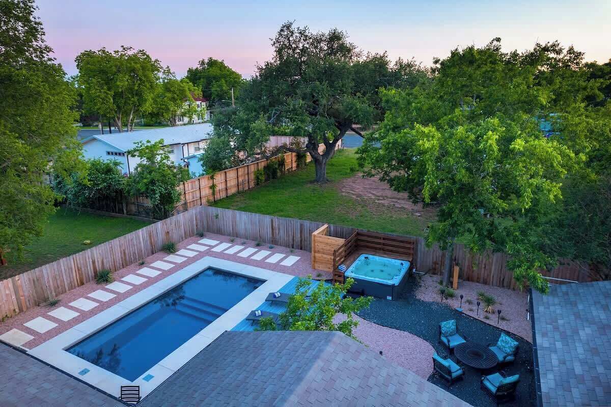 A backyard with a swimming pool, hot tub, and outdoor seating area.